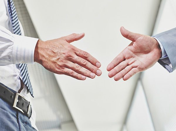 Successful coworkers talking, holding papers and working together. Professional confident office employees standing at table with laptops in conference room. Business, teamwork and management concept